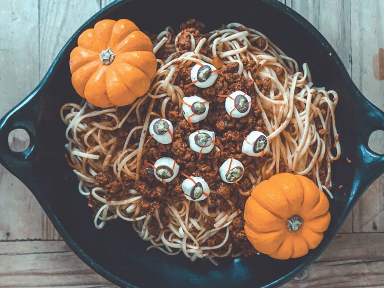 A bowl of spaghetti with Quorn Grounds Bolognese sauce topped with mozzarella 'eyes' and two mini pumpkins as décor.