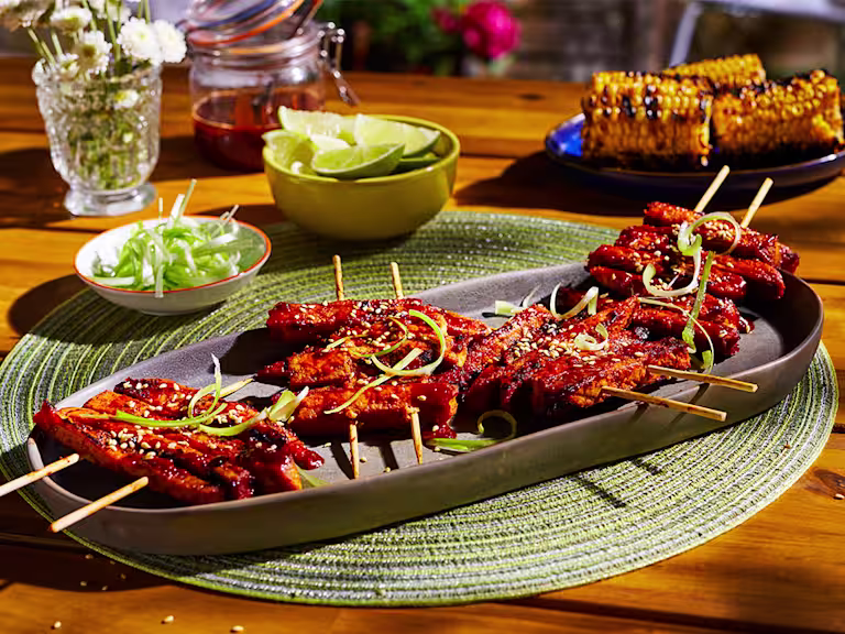 A platter with four servings of Korean BBQ Skewers made with Quorn Meatless ChiQin Fillets topped with sesame and scallions.