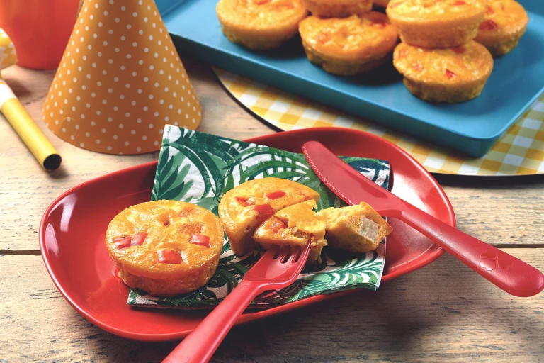 Mini vegetarian quiche with Quorn Pieces served on a leaf print napkin on a red plate with one quiche cut into with a piece on a fork