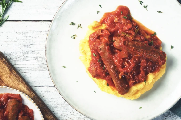Quorn Best of British Sausages in a tomato sauce atop a bed of polenta.