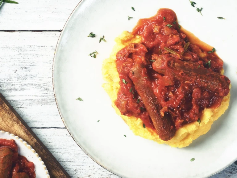 Quorn Best of British Sausages in a tomato sauce atop a bed of polenta.