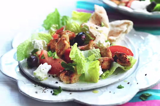 Greek salad made with meat free Quorn Pieces, feta, tomatoes, olives and lettuce served on a flower shaped plate