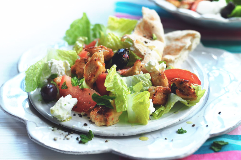 Greek salad made with meat free Quorn Pieces, feta, tomatoes, olives and lettuce served on a flower shaped plate