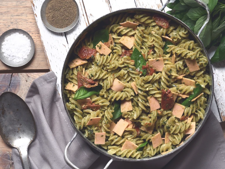 Vegan pasta made with Quorn Gluten Free Vegan Smoky Ham, sundried tomato, basil and fusilli pasta in pesto served in a bowl