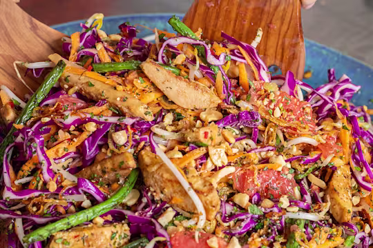 Somebody tossing pickled ginger and grapefruit salad