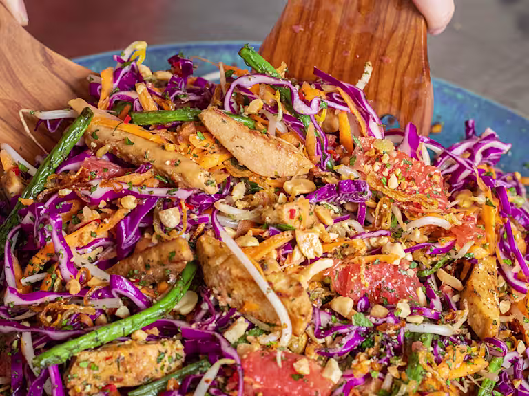 Somebody tossing pickled ginger and grapefruit salad