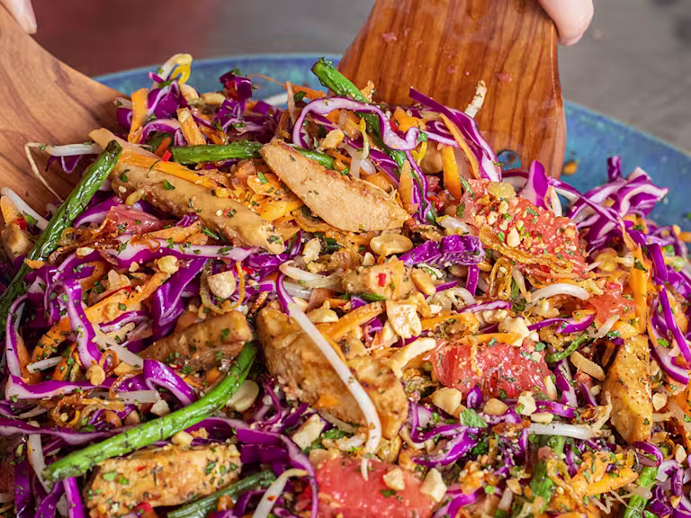 Somebody tossing pickled ginger and grapefruit salad