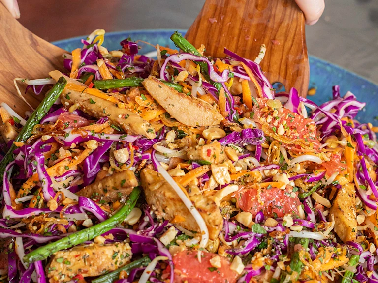 Somebody tossing pickled ginger and grapefruit salad