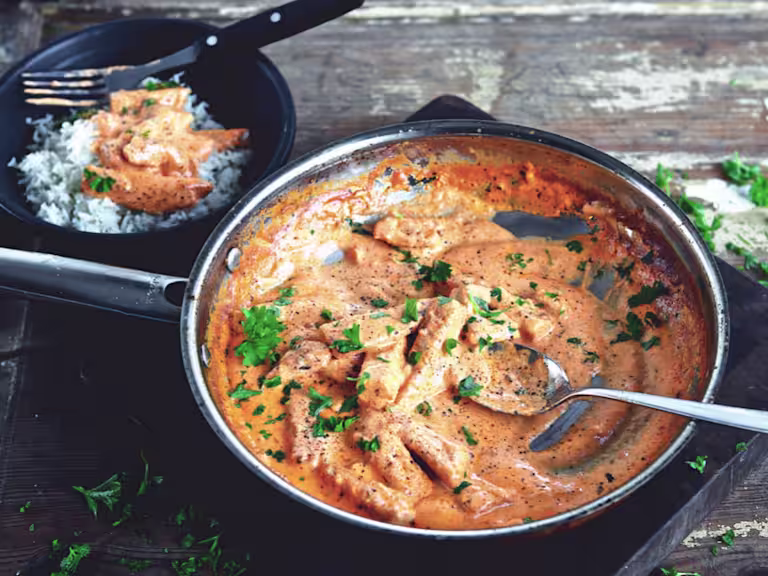 En stor portion Quorn vegetarisk Stroganoff serverad i en svart tallrik, med en sida av ris och toppad med vegetarisk stroganoff i bakgrunden