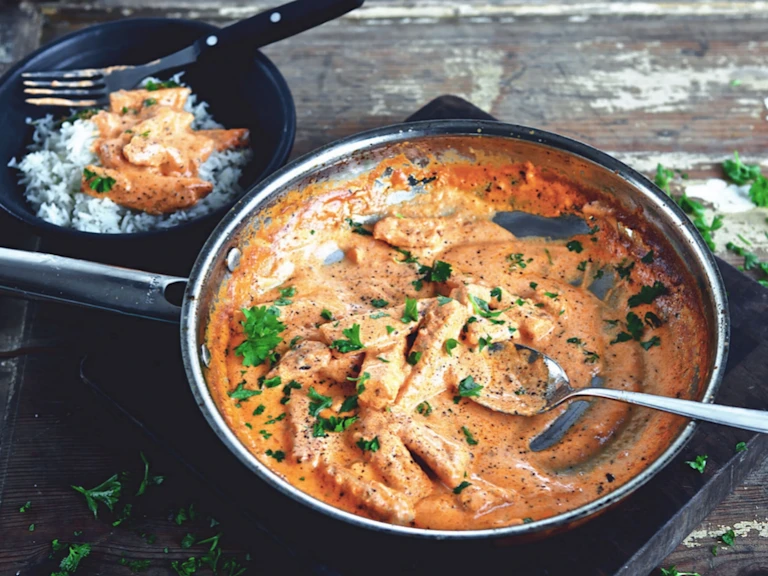 En stor portion Quorn vegetarisk Stroganoff serverad i en svart tallrik, med en sida av ris och toppad med vegetarisk stroganoff i bakgrunden