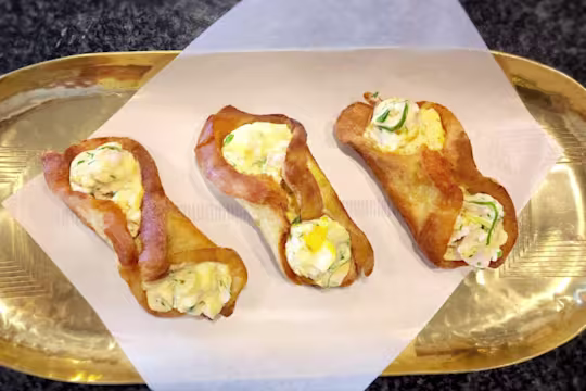 Three fried egg rolls with Quorn Pieces on a gold tray.
