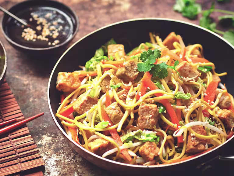 Vegetarian Chow Mein with Quorn Vegetarian Chicken Pieces topped with toasted sesame seeds served on a dark dish.