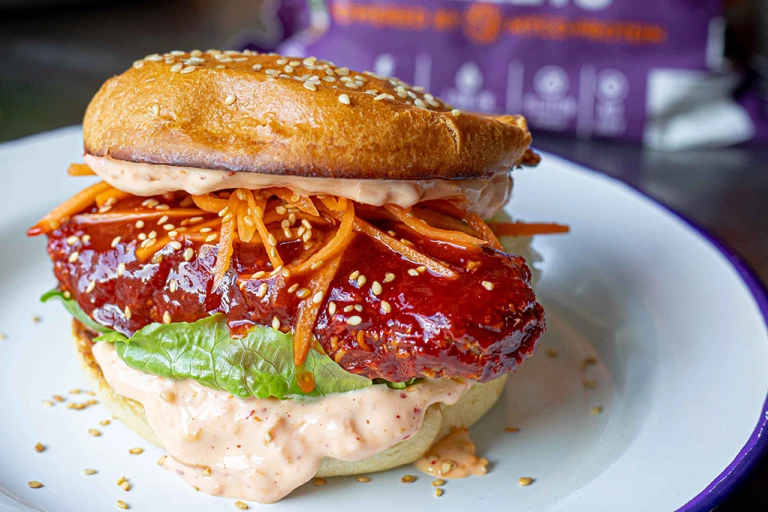 Vegetarian Sweet and Spicy Ramen Burger showing the fillings including grated carrots, lettuce and mayonnaise.