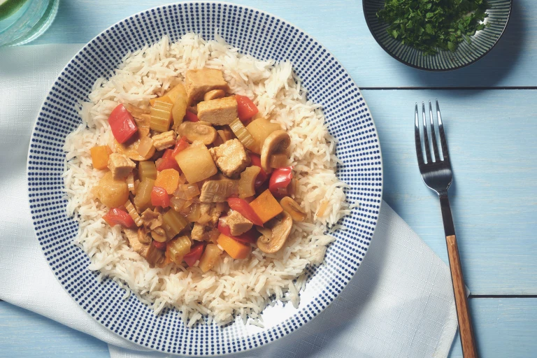 A curry made of Quorn Pieces, mushrooms, peppers, celery, and pineapple atop a bed of white rice.