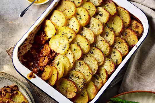 Brilliant Bangers Vegan Hotpot with a slice taken out served in a baking dish.
