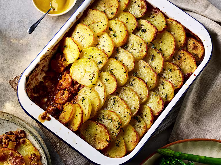 Brilliant Bangers Vegan Hotpot with a slice taken out served in a baking dish.