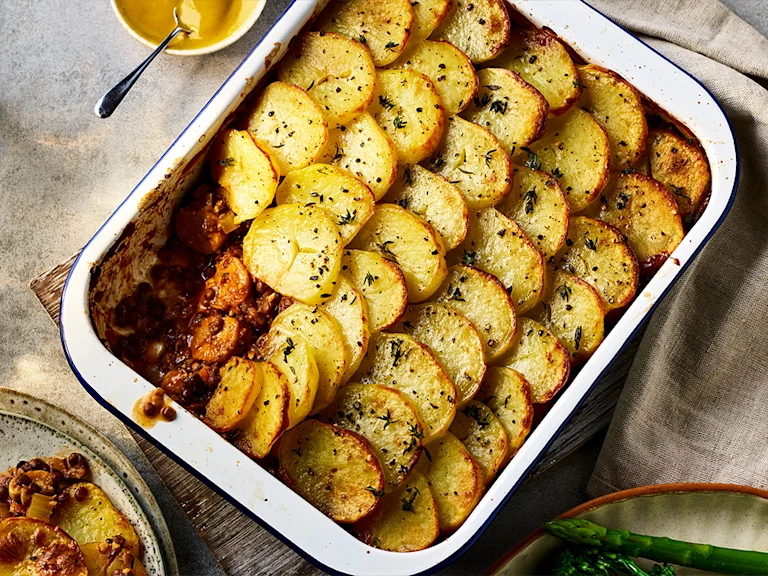 Brilliant Bangers Vegan Hotpot with a slice taken out served in a baking dish.