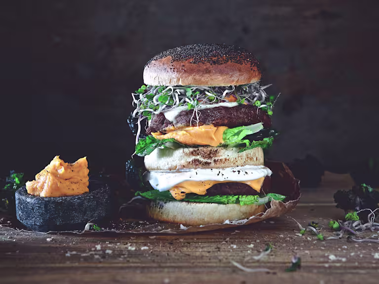 Vegetarian burger made with Quorn Quarter Pounders layered with half a bun, lettuce, cheese, sweet potato mash and beansprouts
