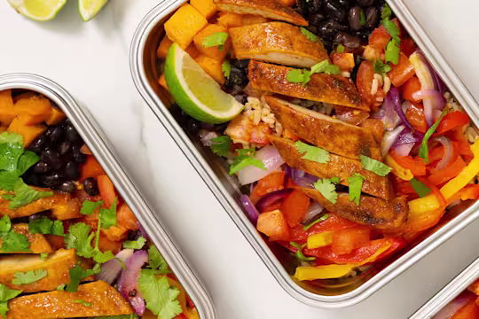 Vegetables, black beans and Quorn fillets served in a steel tin with sliced limes on the side.