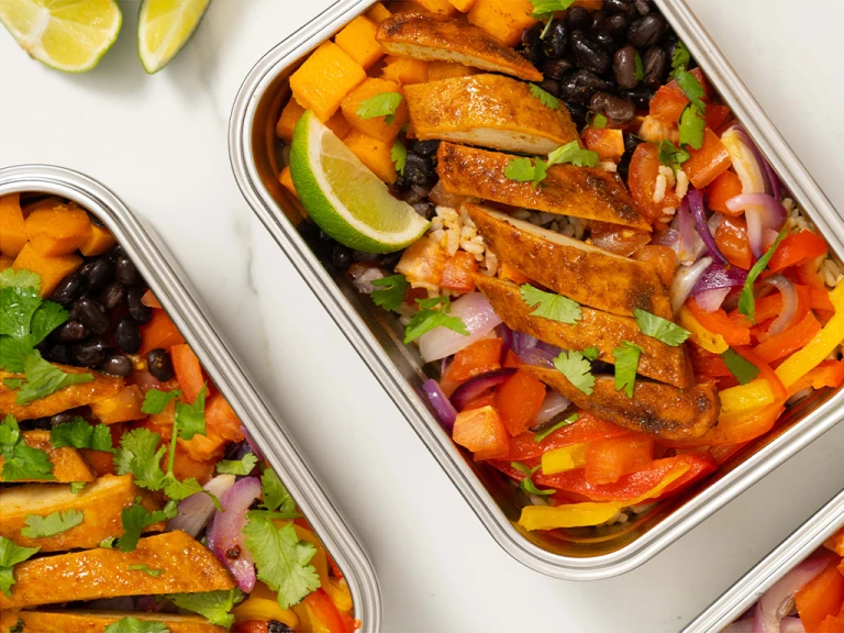 Vegetables, black beans and Quorn fillets served in a steel tin with sliced limes on the side.