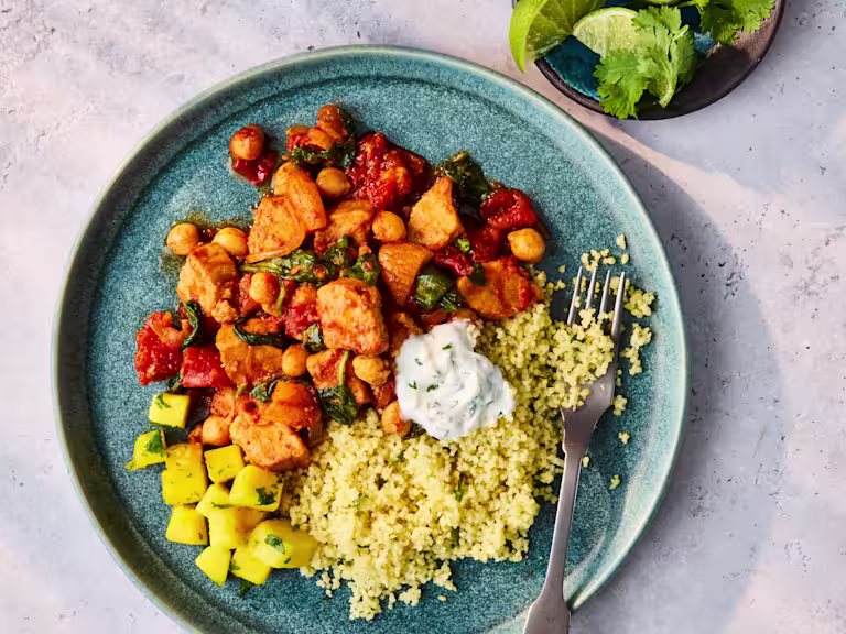 Plated Quorn Pieces Tagine with couscous, herbed yogurt, and a side of mango salad.
