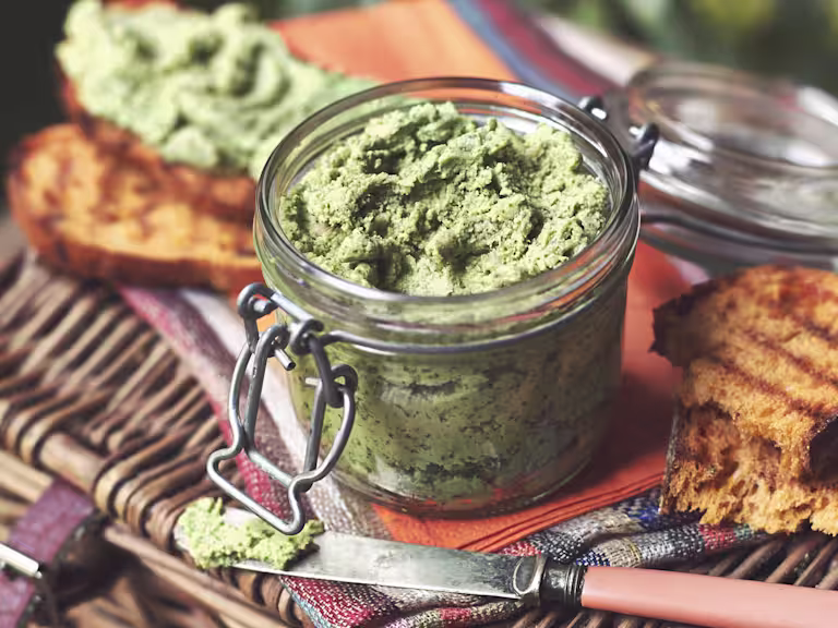 Vegetarian pate made with Quorn Pieces and spinach served in a jar on top of a picnic basket and toasted bread on the side