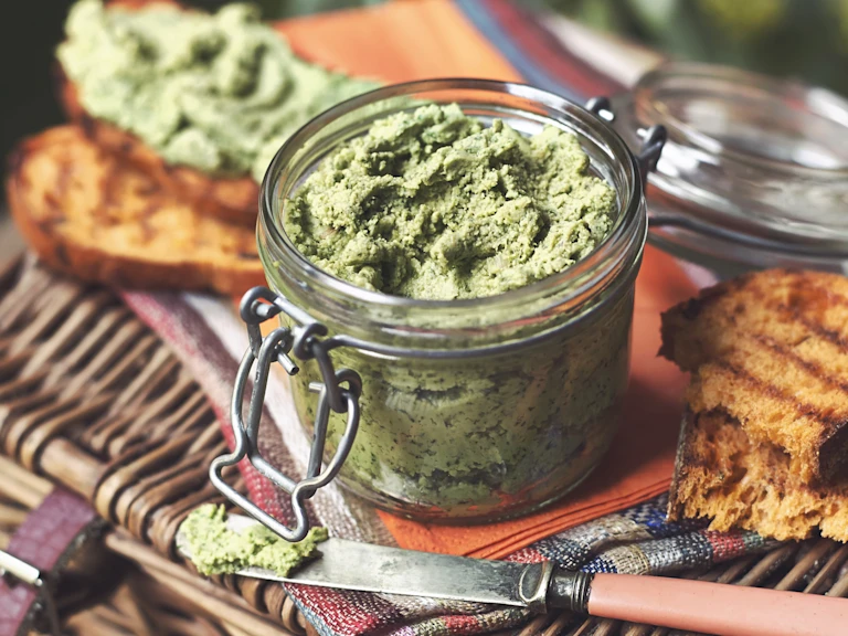 Vegetarian pate made with Quorn Pieces and spinach served in a jar on top of a picnic basket and toasted bread on the side