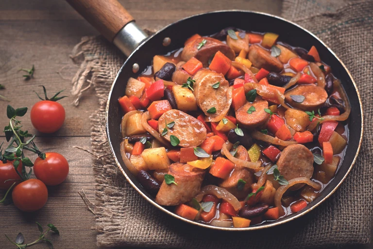 A stew of Quorn sausages, beans, and mixed vegetables in a pan.