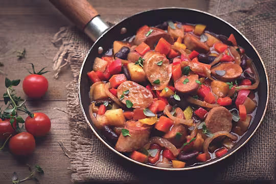 A stew of Quorn sausages, beans, and mixed vegetables in a pan.