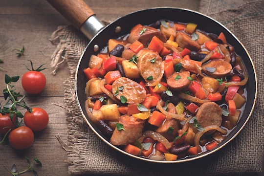 A stew of Quorn sausages, beans, and mixed vegetables in a pan.