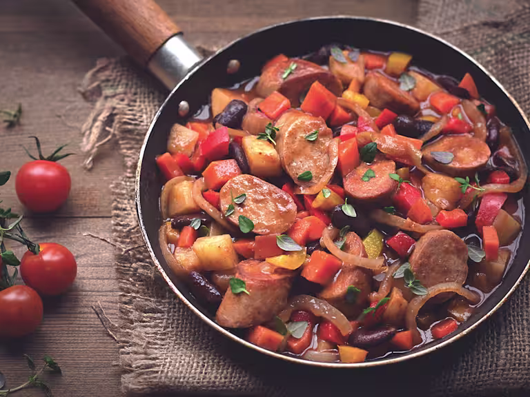 A stew of Quorn sausages, beans, and mixed vegetables in a pan.