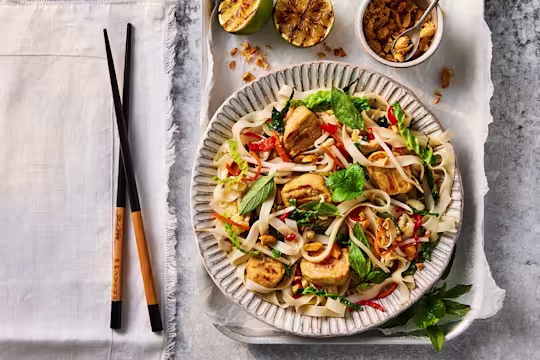 A bowl of Quorn Pad Thai made using Quorn Vegetarian Chicken Fillet Pieces next to a set of chopsticks.