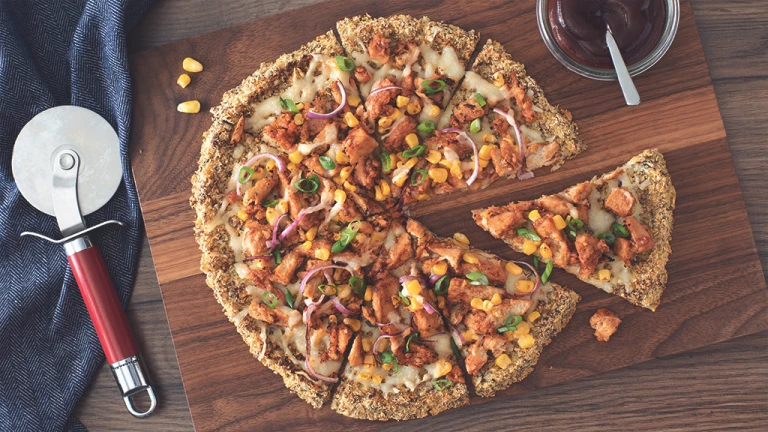 A vegan pizza on a cauliflower crust topped with Quorn Vegan Pieces, red onion, sweetcorn, and vegan cheese.