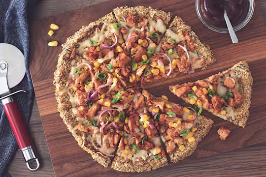 A vegan pizza on a cauliflower crust topped with Quorn Vegan Pieces, red onion, sweetcorn, and vegan cheese.