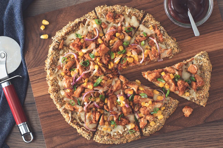 A vegan pizza on a cauliflower crust topped with Quorn Vegan Pieces, red onion, sweetcorn, and vegan cheese.