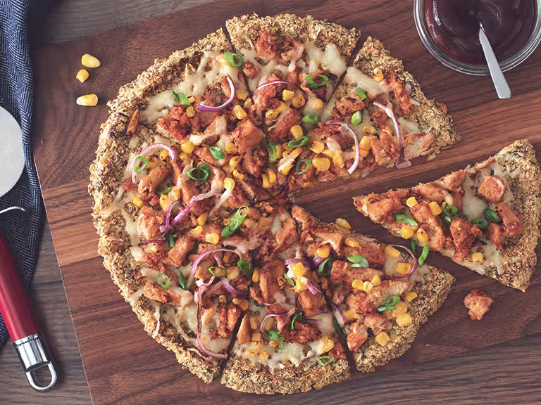 A vegan pizza on a cauliflower crust topped with Quorn Vegan Pieces, red onion, sweetcorn, and vegan cheese.