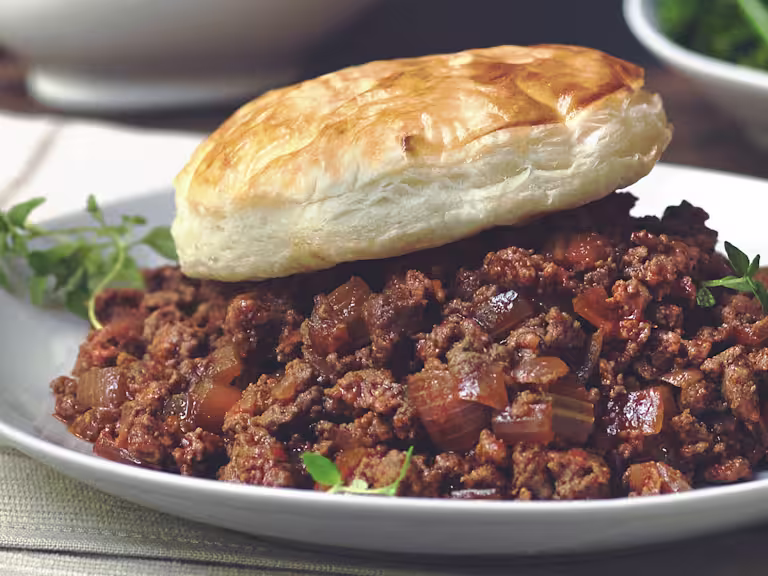 Vegetarian pie made with Quorn Mince and onions served on a plate topped with a pastry lid and sprigs of thyme