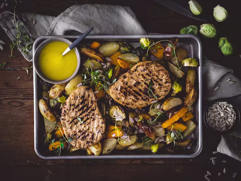 Quorn Vegetarian Steak strips with mushrooms in an orange sauce served in a dish garnished with herbs next to a dish of rice