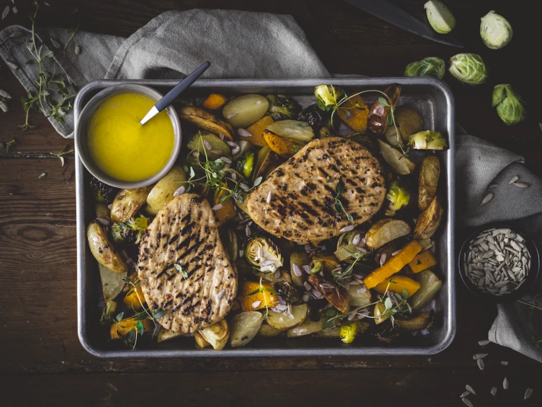 Quorn Vegetarian Steak strips with mushrooms in an orange sauce served in a dish garnished with herbs next to a dish of rice