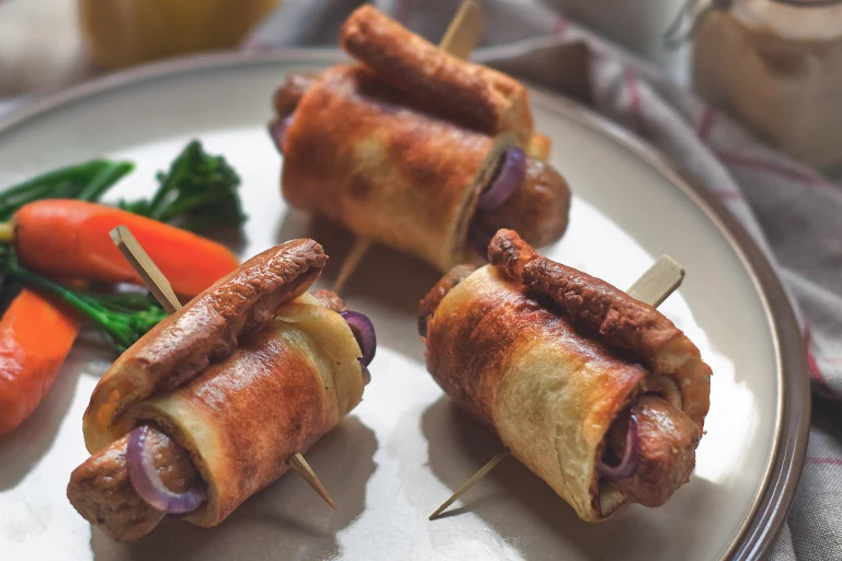 Vegetarian toad in the hole with Quorn Sausages and onion wrapped in Yorkshire pudding skewered with a cocktail stick on a plate