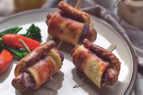 Vegetarian toad in the hole with Quorn Sausages and onion wrapped in Yorkshire pudding skewered with a cocktail stick on a plate