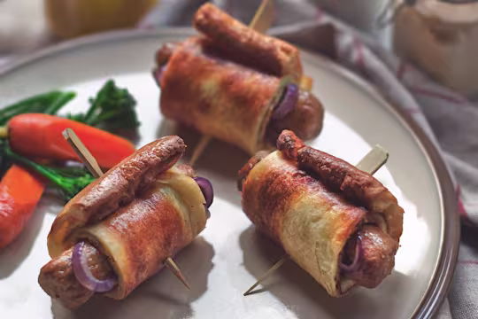 Vegetarian toad in the hole with Quorn Sausages and onion wrapped in Yorkshire pudding skewered with a cocktail stick on a plate