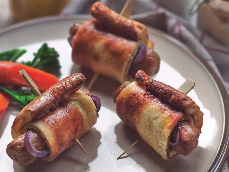 Vegetarian toad in the hole with Quorn Sausages and onion wrapped in Yorkshire pudding skewered with a cocktail stick on a plate