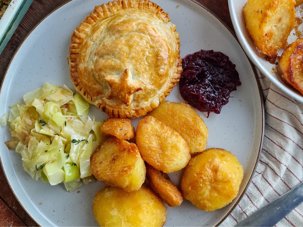 A Mini Vegetarian Turkey & Stuffing Wellington on a white plate with cranberry sauce.