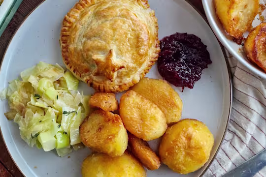 A Mini Vegetarian Turkey & Stuffing Wellington on a white plate with cranberry sauce.