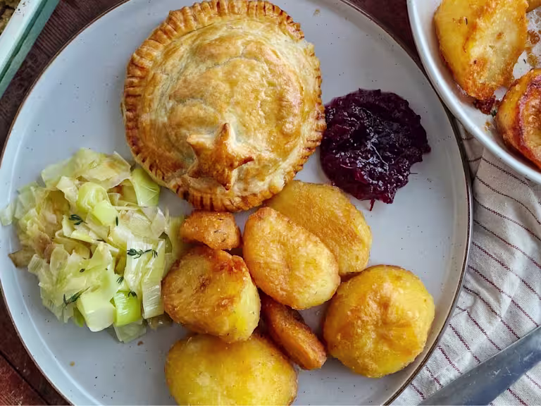 A Mini Vegetarian Turkey & Stuffing Wellington on a white plate with cranberry sauce.