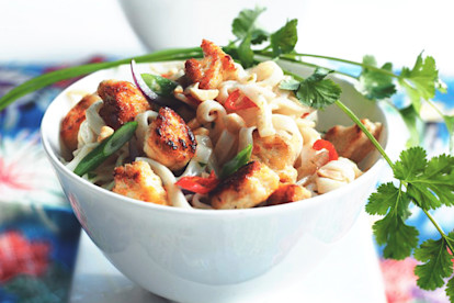 A white bowl of pad Thai noodles topped with green onions, chilis, Quorn Pieces and a sprig of cilantro.