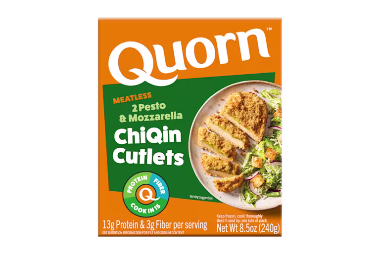 A box of Quorn Meatless Pesto & Mozzarella Cutlets showing the plated product and information on a charcoal and orange background.