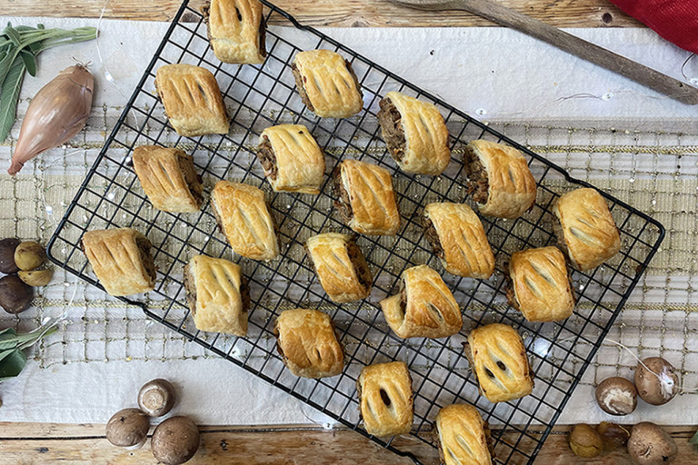 Vegan sausage rolls served on a cooling rack with mushrooms on the side