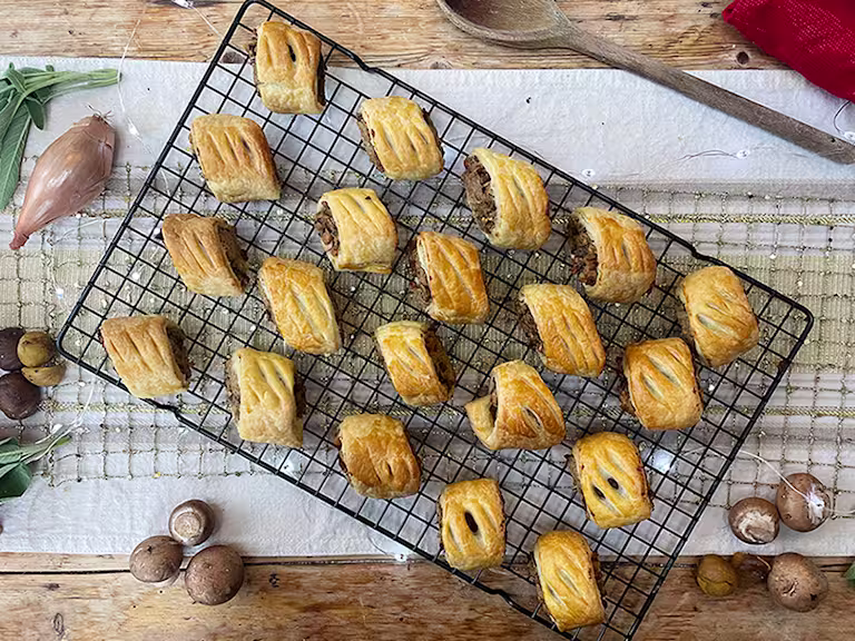 Vegan sausage rolls served on a cooling rack with mushrooms on the side